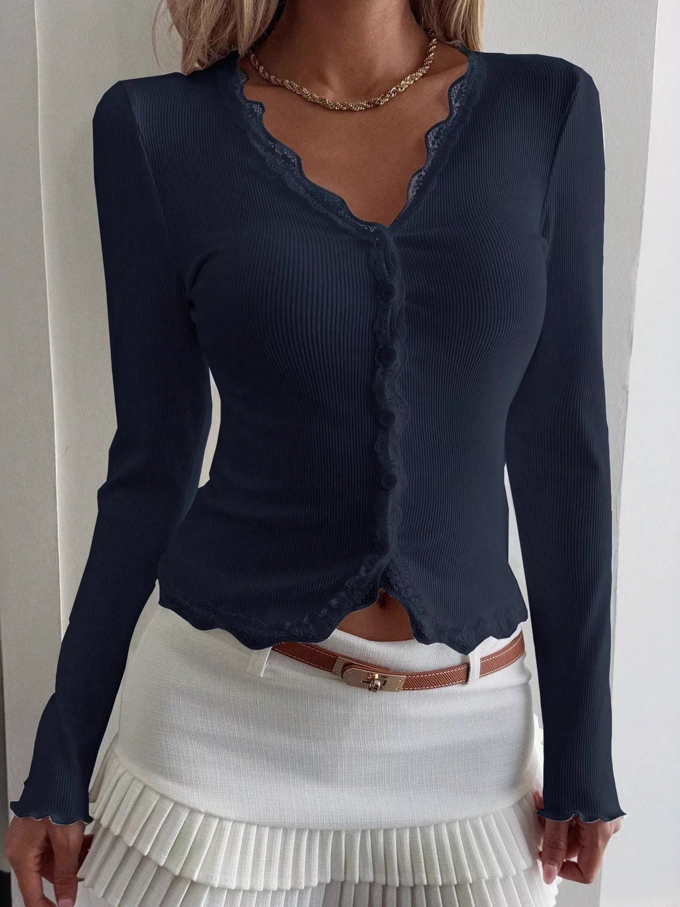 Navy blue long-sleeve top with scalloped neckline worn by a person on a plain background