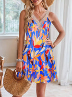 Woman wearing a colorful floral dress holding a straw bag indoors.