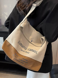 Beige and brown tote bag with 'Aimanqi canvas market' branding held by a person.