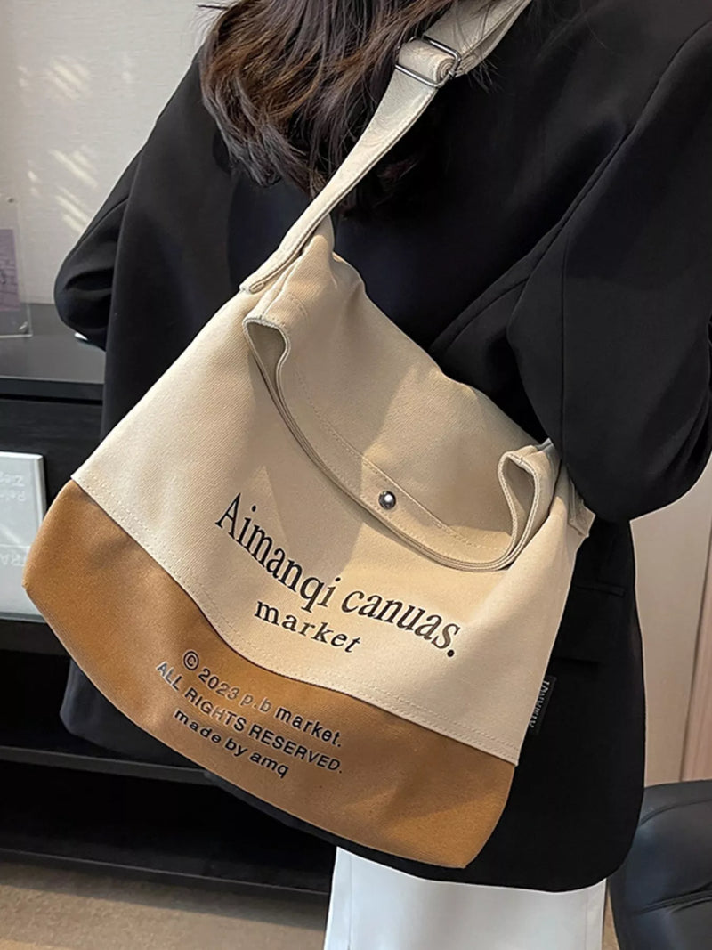 Beige and brown tote bag with 'Aimanqi canvas market' branding held by a person.