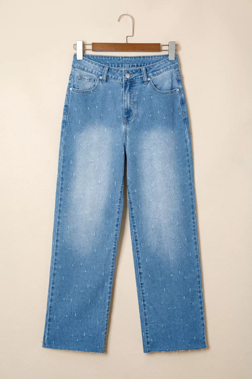 Blue jeans on a hanger against a beige background