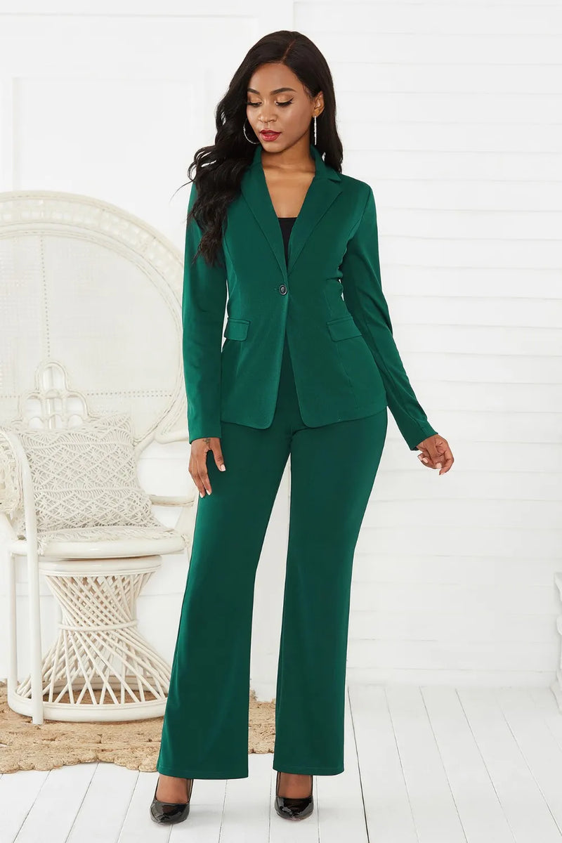 Woman wearing a green suit standing in a minimalistic room with a white chair.