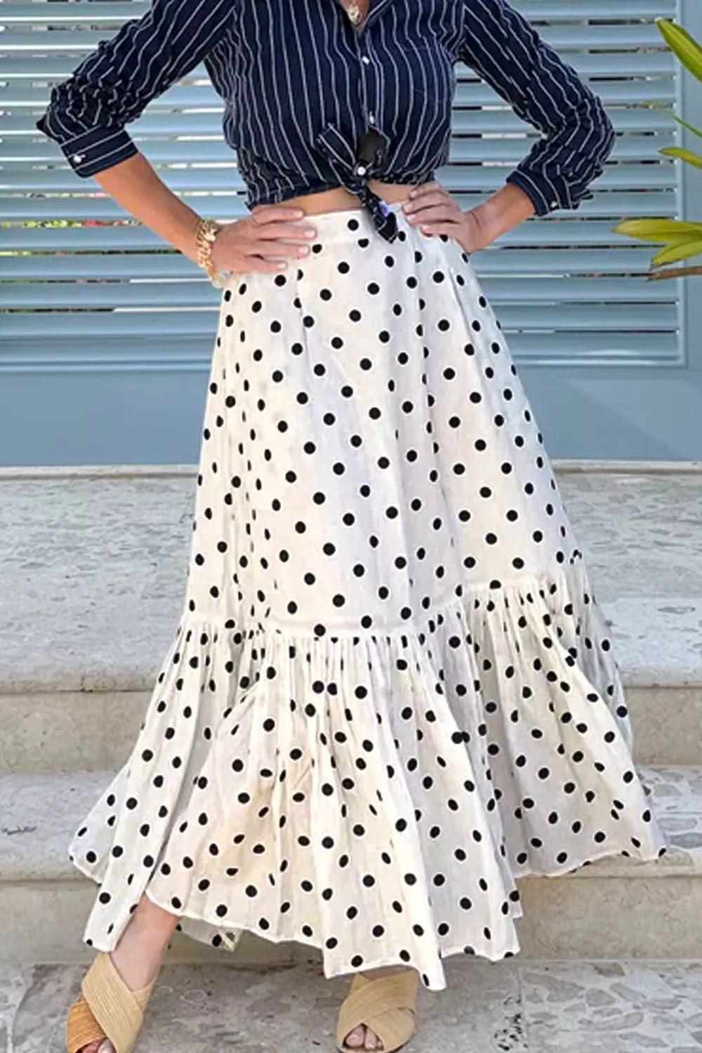 Person wearing a polka dot skirt and striped shirt on steps.