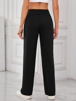 Person wearing black high-waisted pants in a minimalistic setting