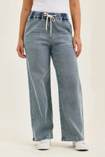Light blue jeans with a drawstring waist on a plain background