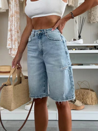 Person wearing light blue denim shorts with a white top in an indoor setting.