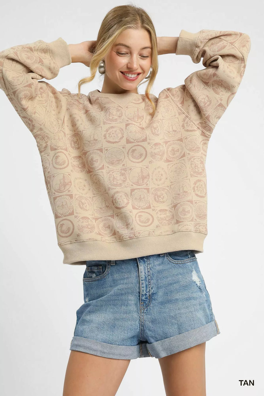 Woman wearing a beige textured sweatshirt and denim shorts on a white background