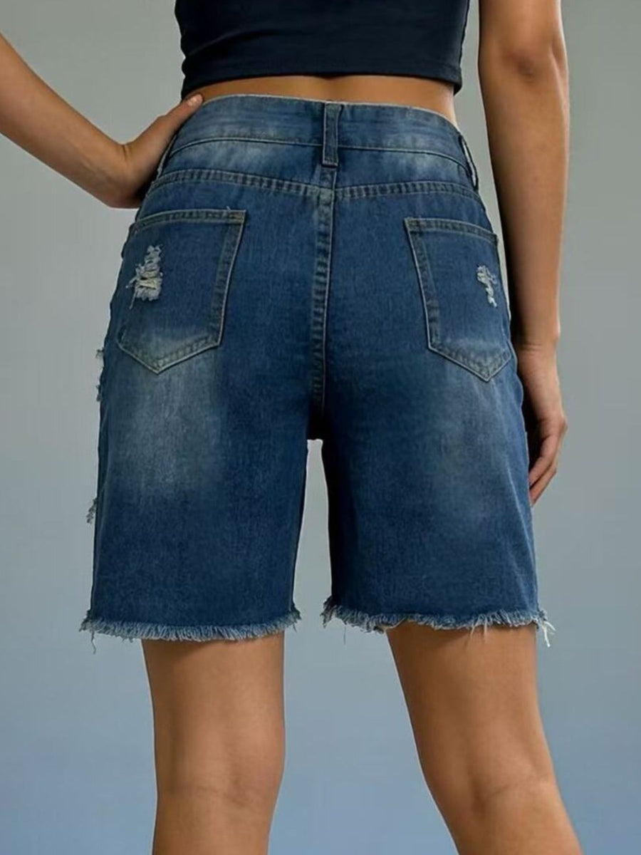 Blue denim shorts worn by a person on a gray background