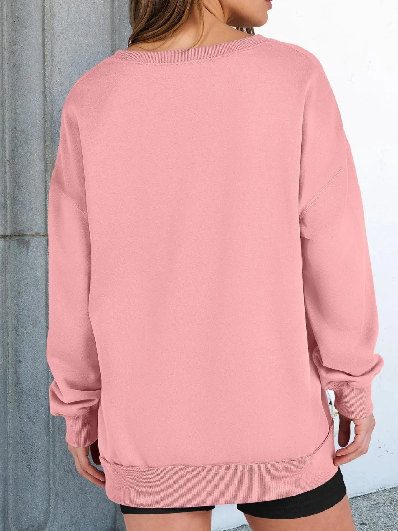 Person wearing a pink sweatshirt with a neutral background