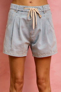 Light blue denim shorts with a drawstring on a pink background
