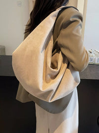 Person wearing a beige oversized sweater in an indoor setting