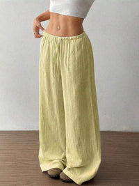 Person wearing light green wide-leg pants on a plain background