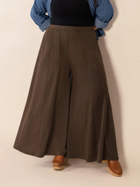 Brown wide-leg pants worn by a person on a beige background
