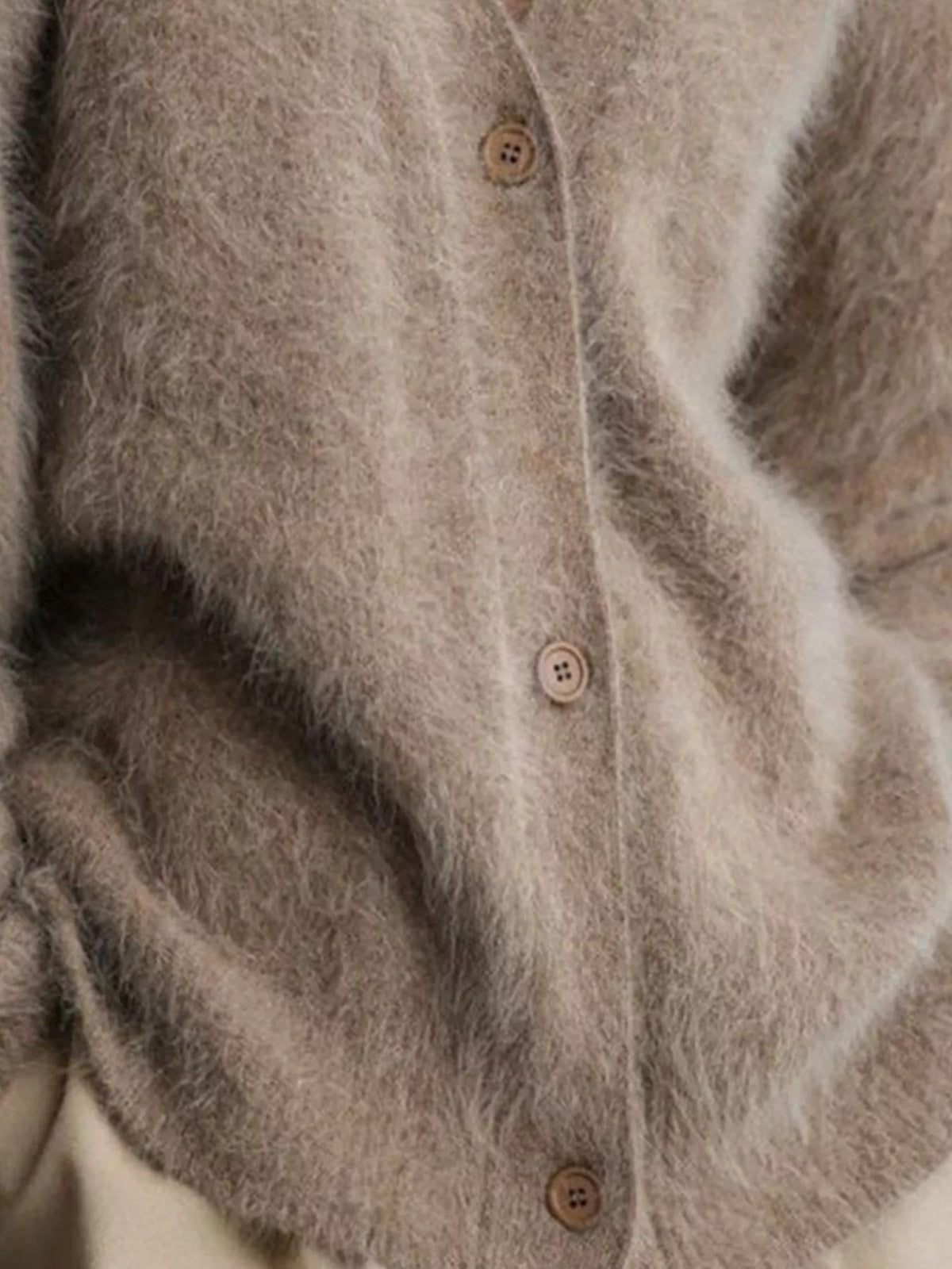Close-up of a textured beige cardigan with button details