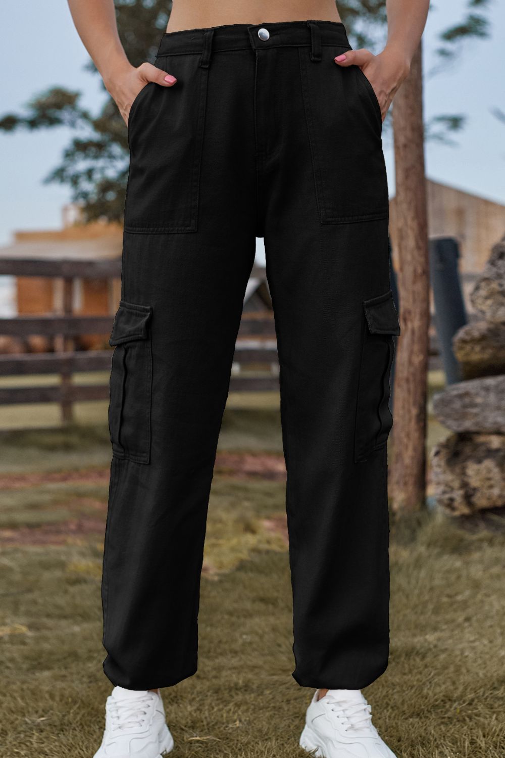 Person wearing black cargo pants standing outdoors with a blurred background