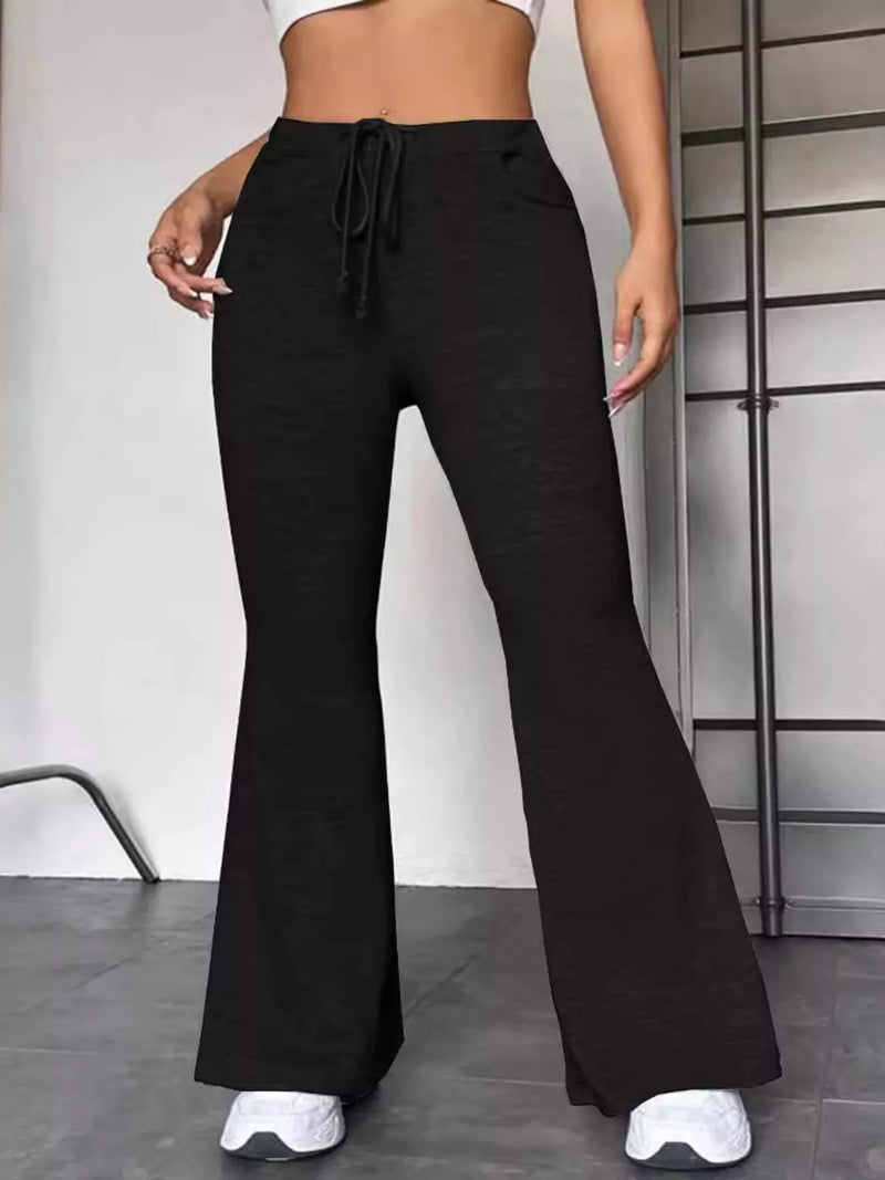 Person wearing black flared pants with a white background