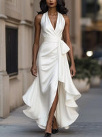 Woman wearing a white dress with a high slit on a city street.