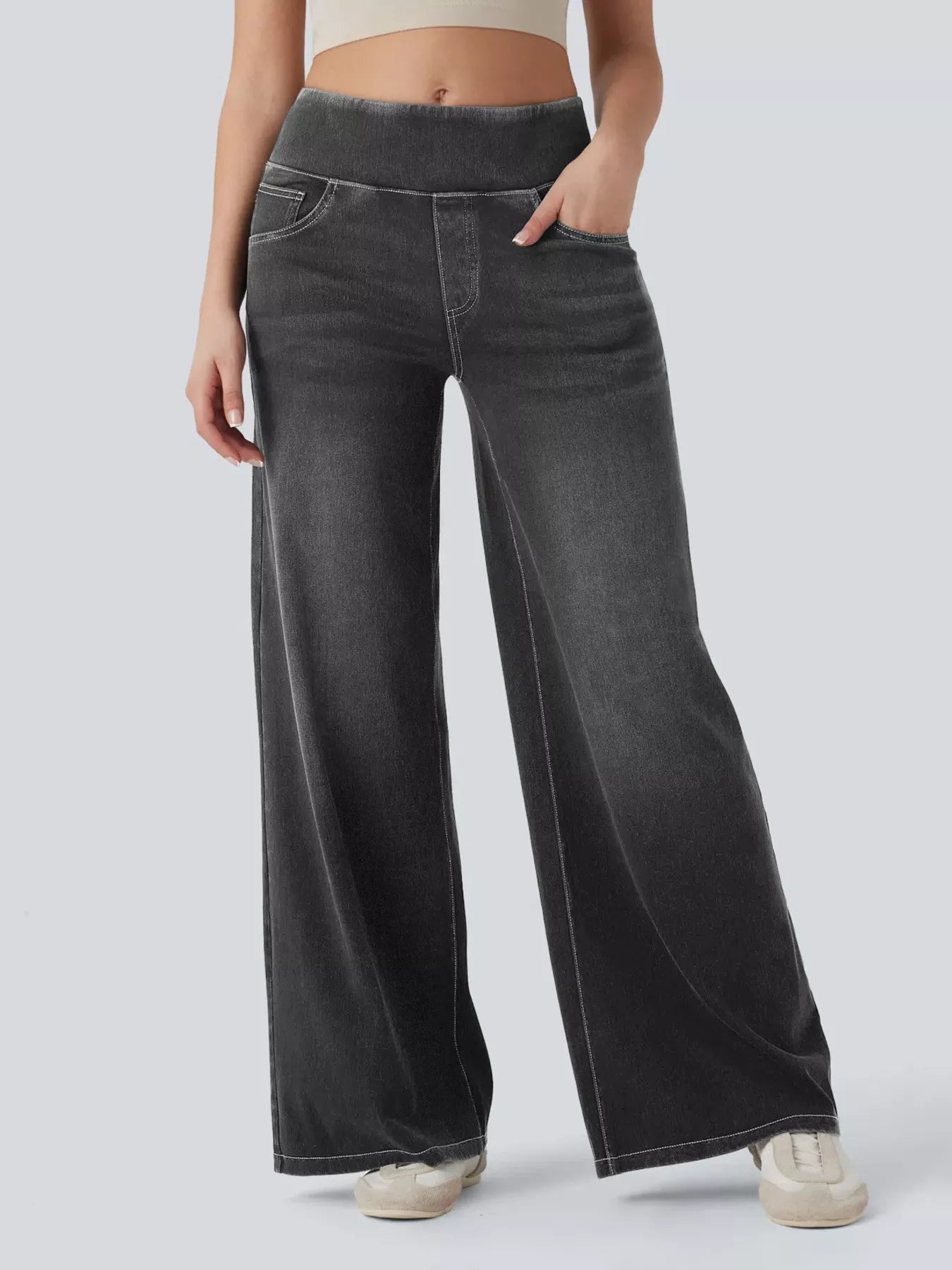 Person wearing black wide-leg jeans on a light gray background