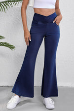 Person wearing navy flared pants with a white background