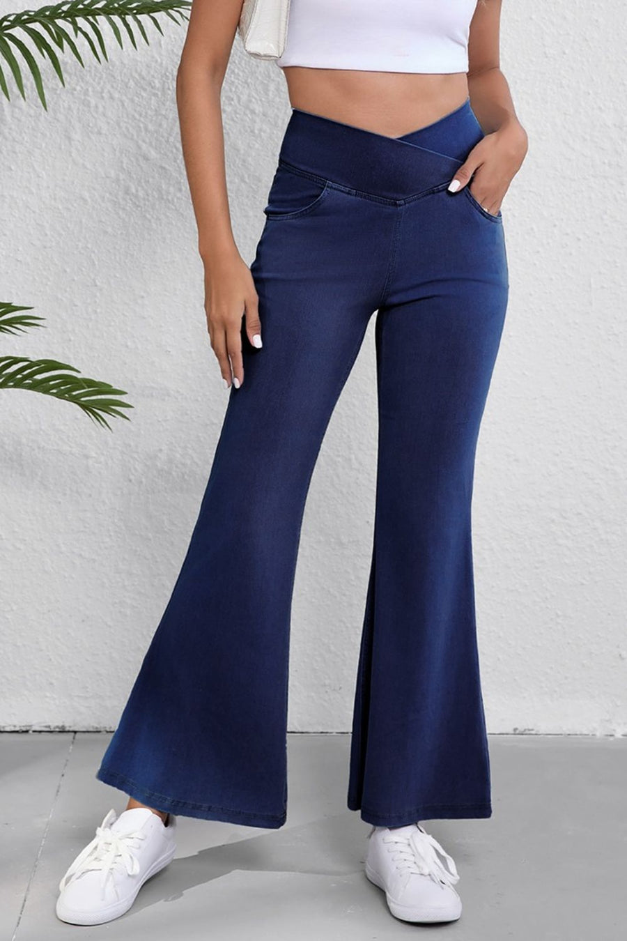 Person wearing navy flared pants with a white background