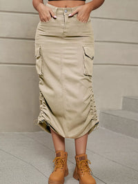 Person wearing a beige cargo skirt and brown boots against a neutral background