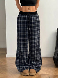 Person wearing black and white plaid pants on a wooden floor.