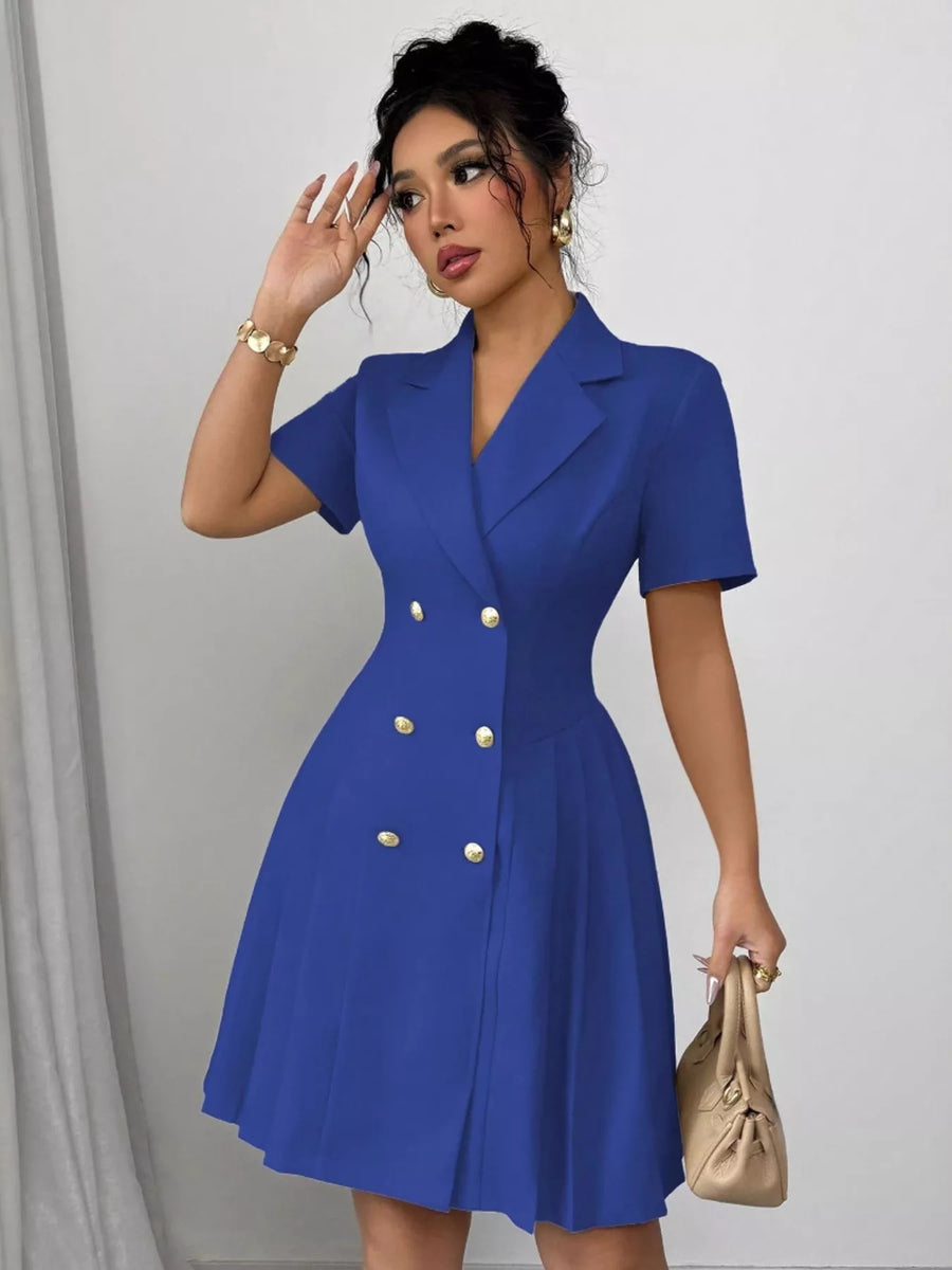 Woman wearing a blue dress with gold buttons against a plain background