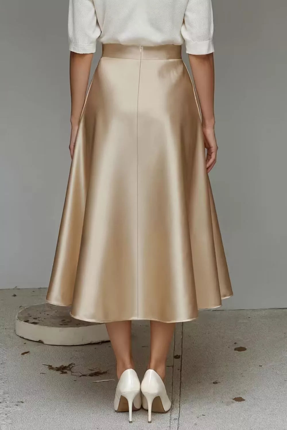 Person wearing a gold skirt and white shoes on a neutral background