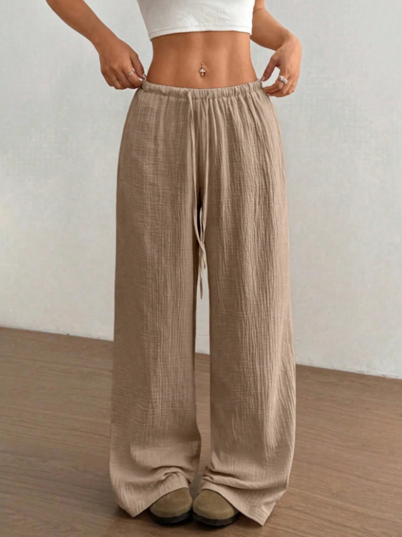 Person wearing beige wide-leg pants against a plain background
