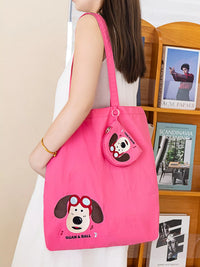 Person holding a pink tote bag with a cartoon dog design in front of a bookshelf.
