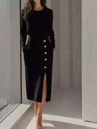 Woman wearing a black dress with white buttons in a minimalistic setting