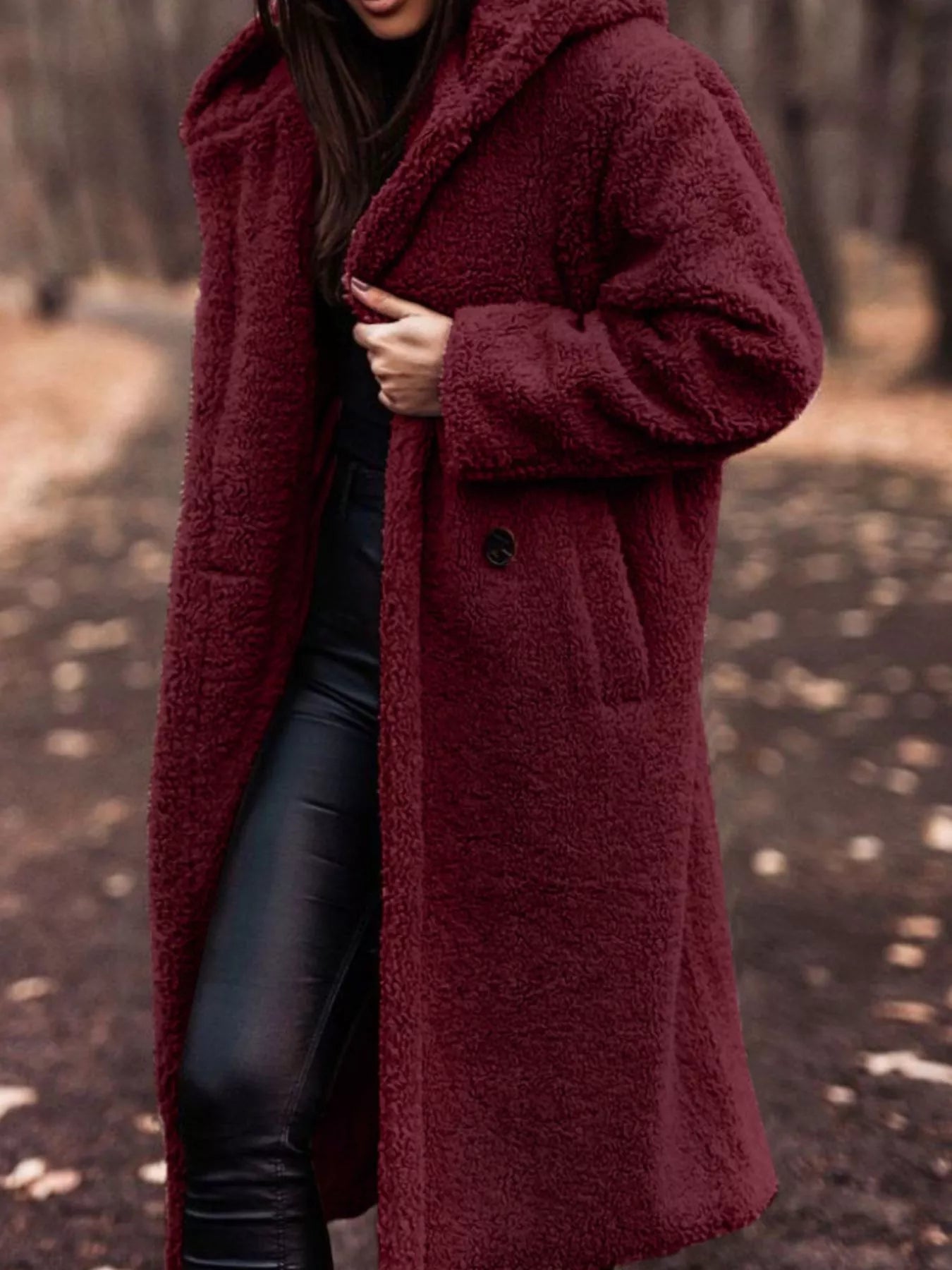 Person wearing a burgundy coat in a forest setting