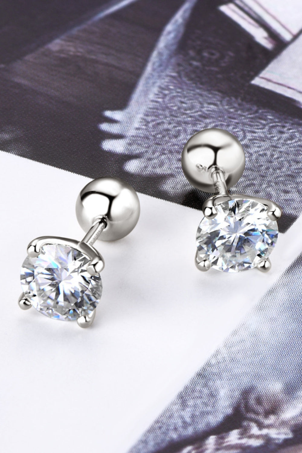 Silver earrings with clear gemstones on a textured surface