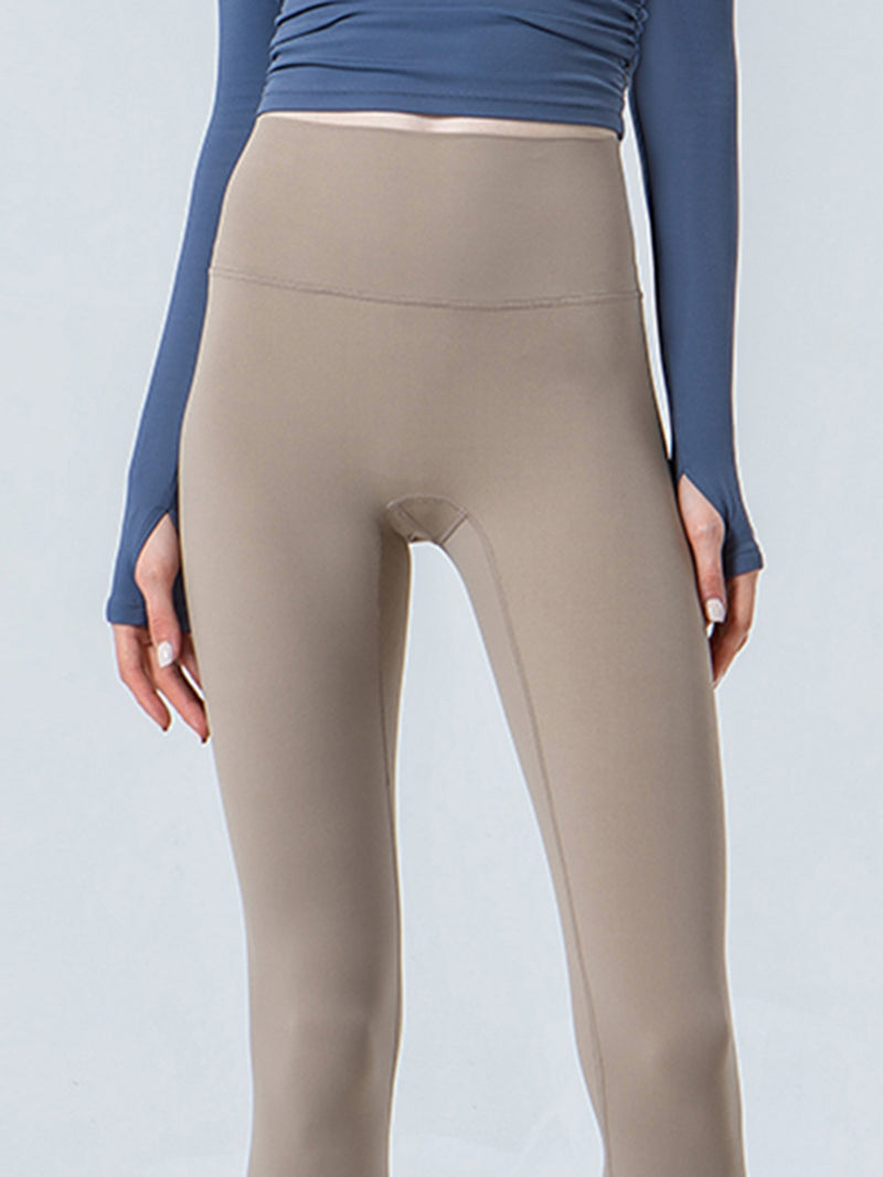 Beige leggings worn with a blue long-sleeve top on a light gray background