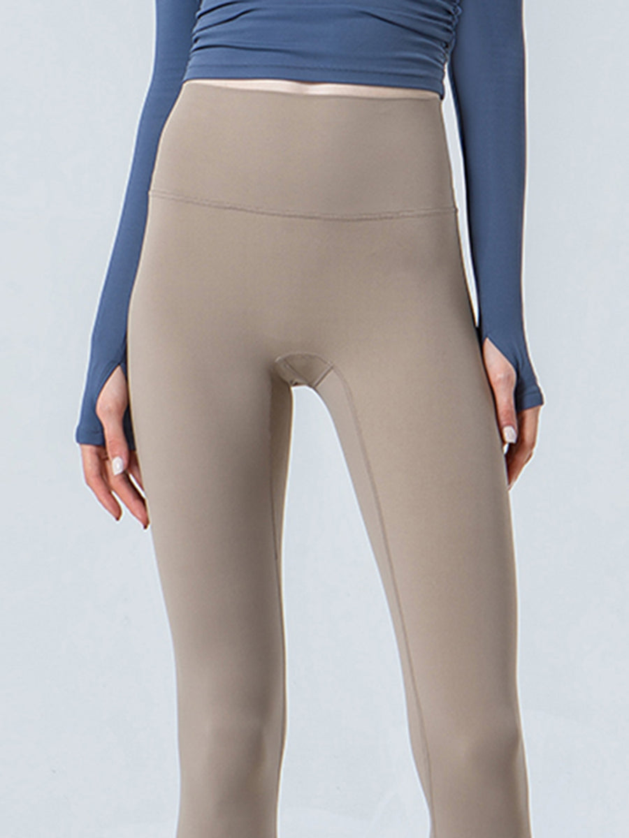 Beige leggings worn with a blue long-sleeve top on a light gray background