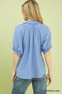 Woman wearing a blue blouse with ruffled collar on a light green background