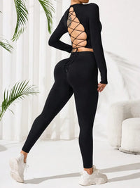Person wearing a black outfit with lace-up back design in a minimalistic setting.