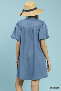 Woman wearing a light denim dress and straw hat on a light blue background