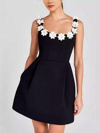 Black dress with white floral shoulder details on a plain background