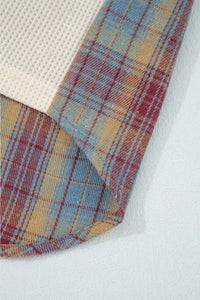 Close-up of a plaid fabric with red, blue, and yellow colors on a white background.