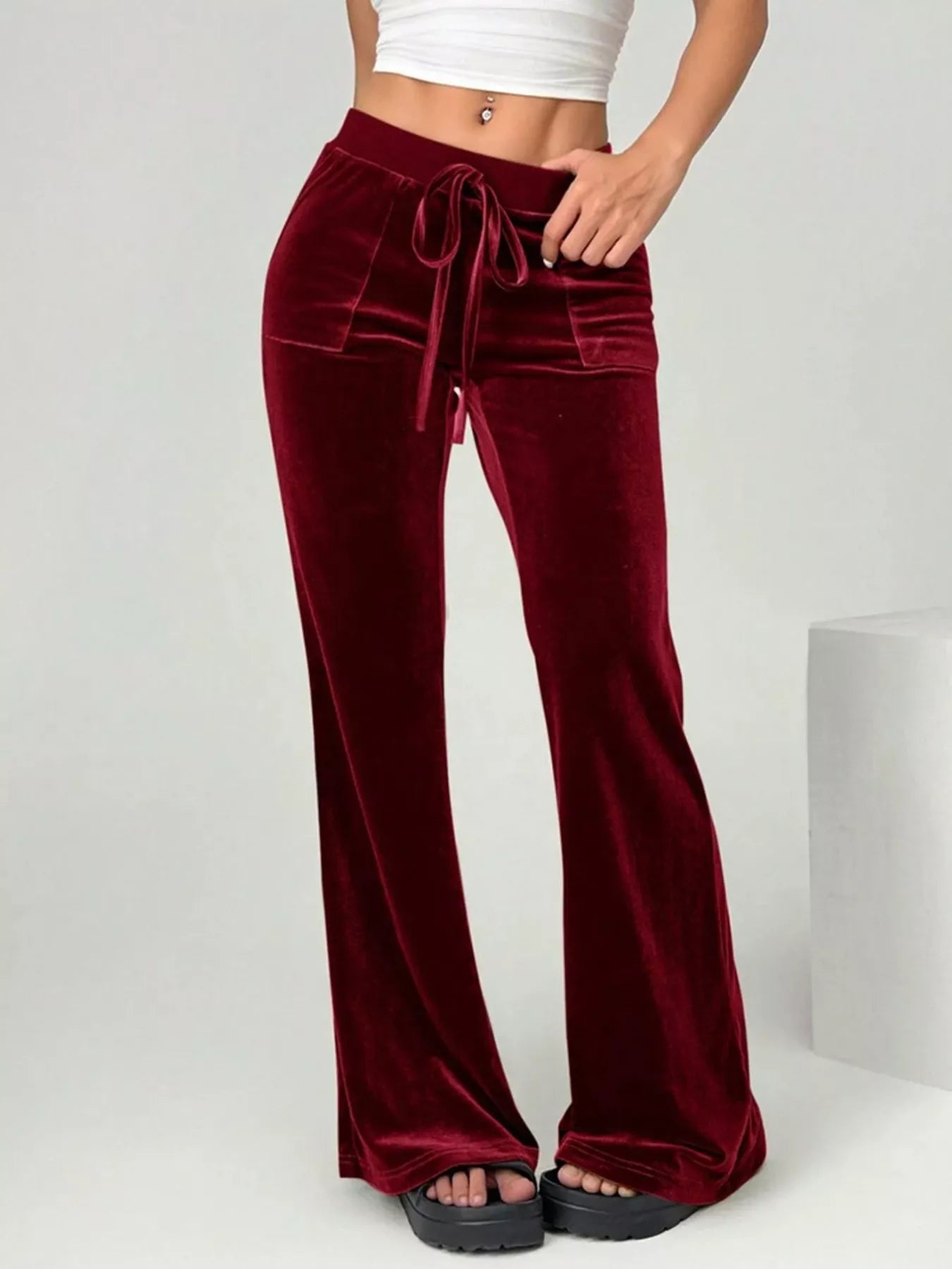 Maroon velvet pants with a white top on a light gray background