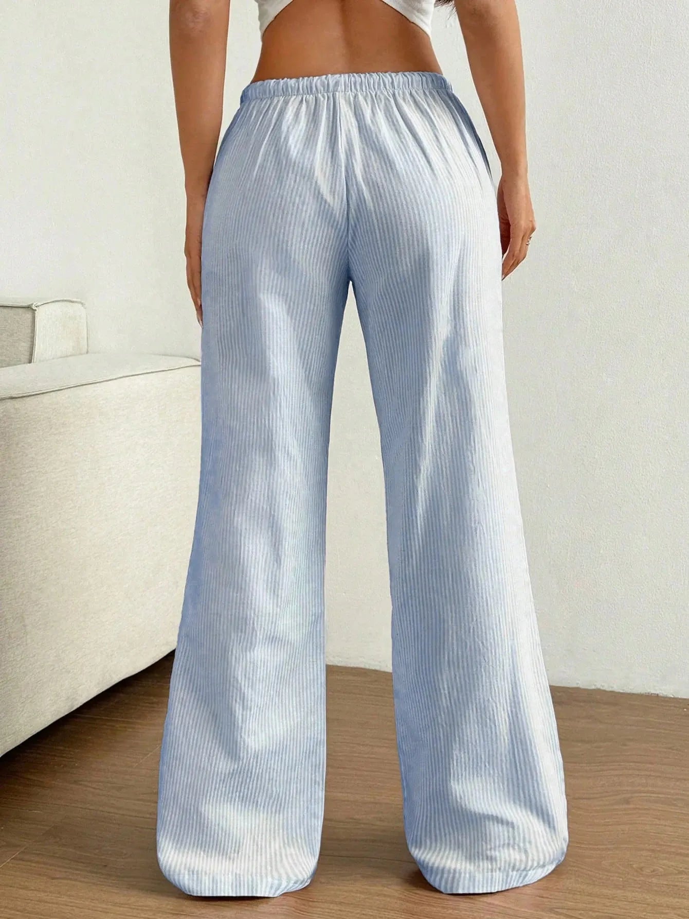 Person wearing light blue and white striped pants on a neutral background