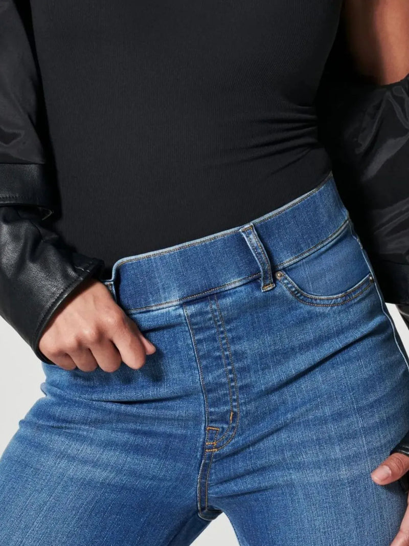 Person wearing blue jeans and a black leather jacket on a light gray background