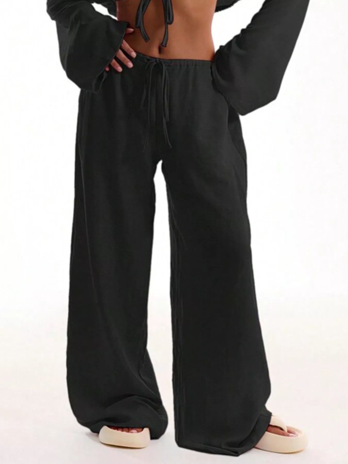 Black wide-leg pants worn by a person on a white background