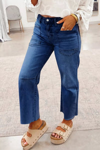 Person wearing blue jeans and sandals in a room with a chair and rug.