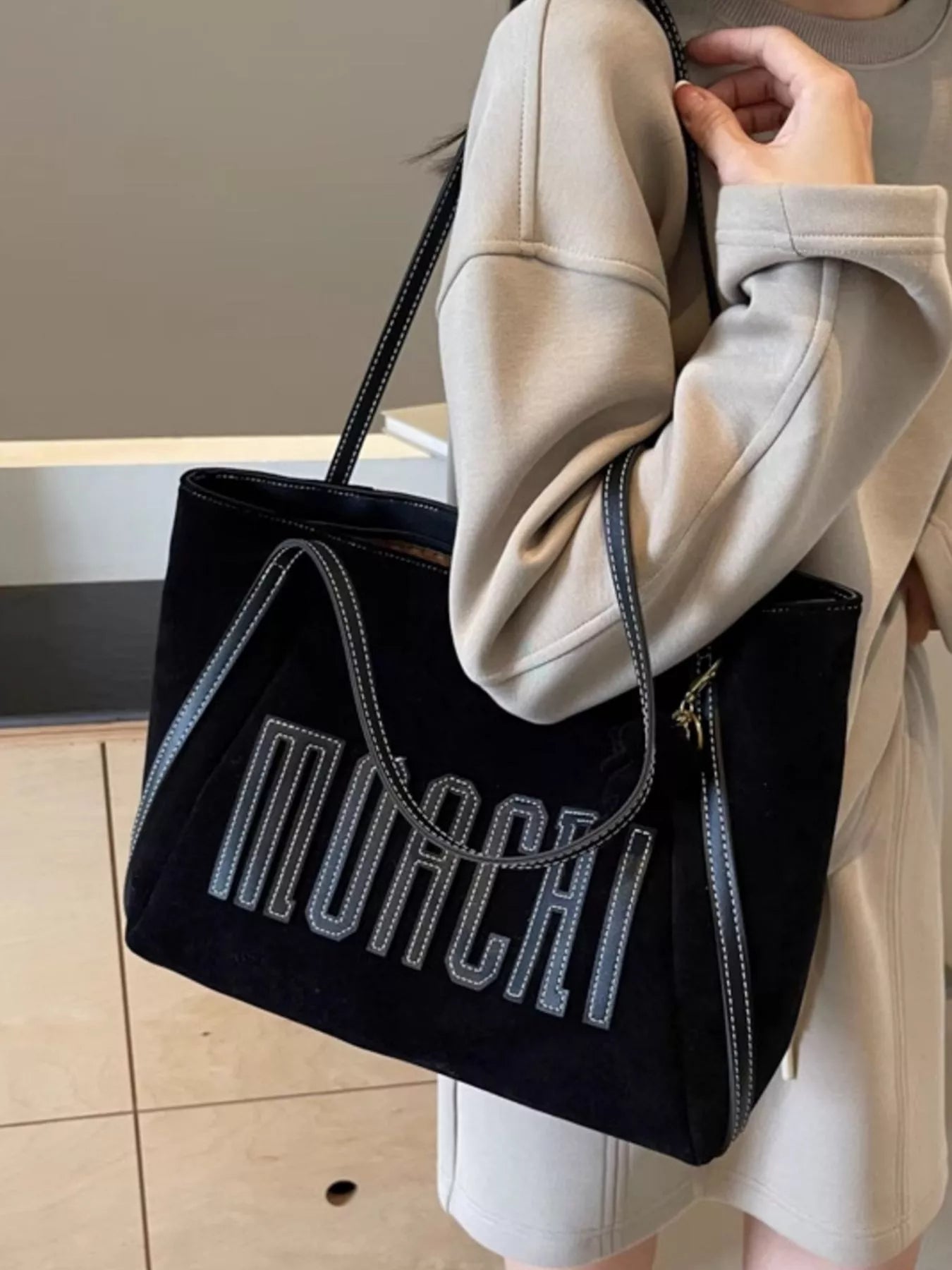 Person holding a black tote bag with 'Mochi' branding.