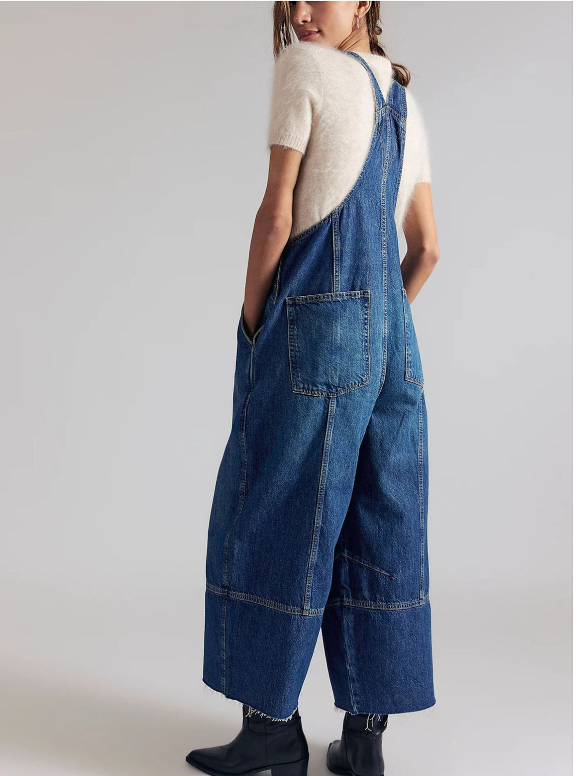 Person wearing blue denim overalls on a plain background