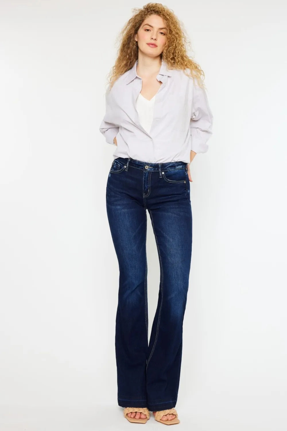 Woman wearing a light gray shirt and blue jeans on a white background