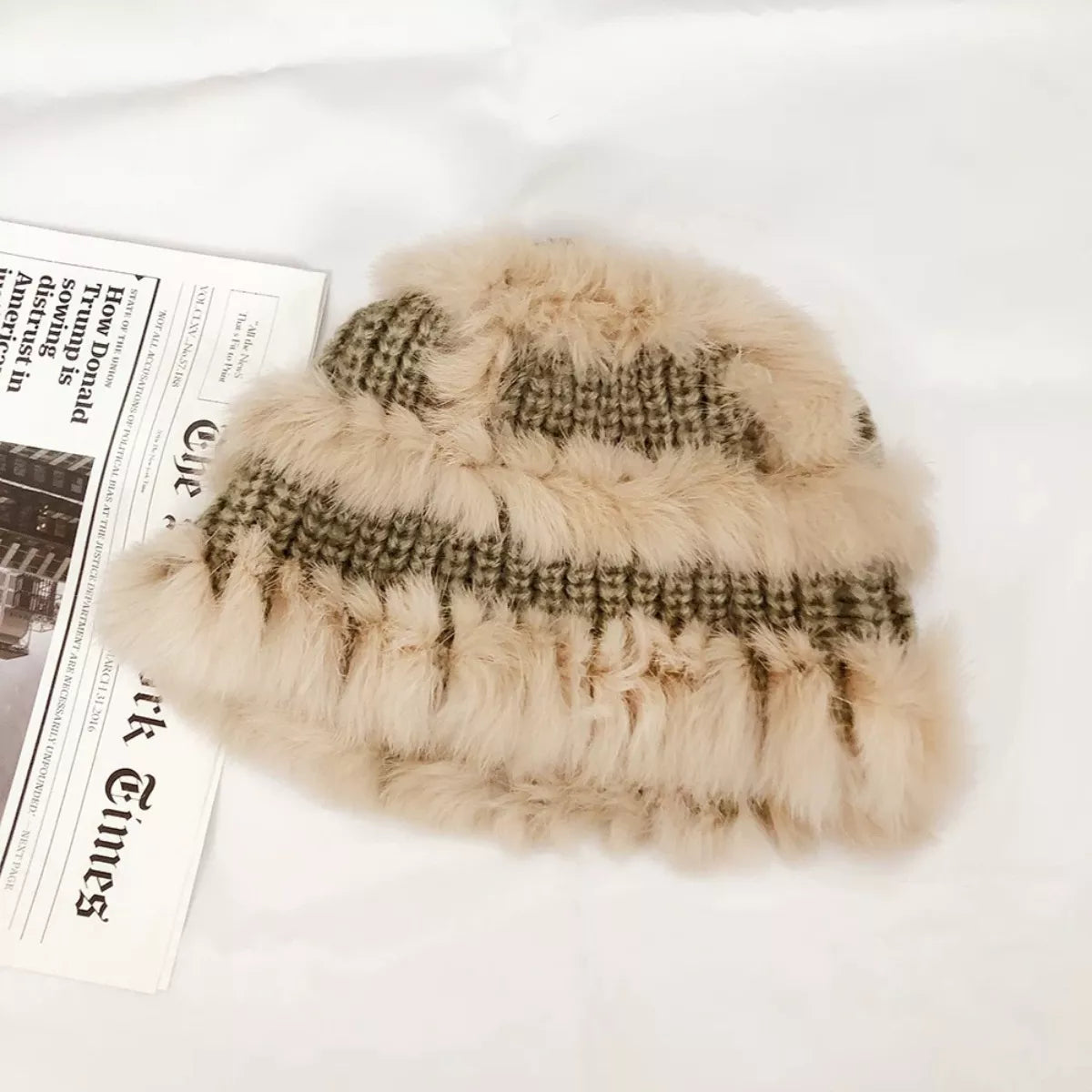 Beige fur hat with plaid pattern on a white surface