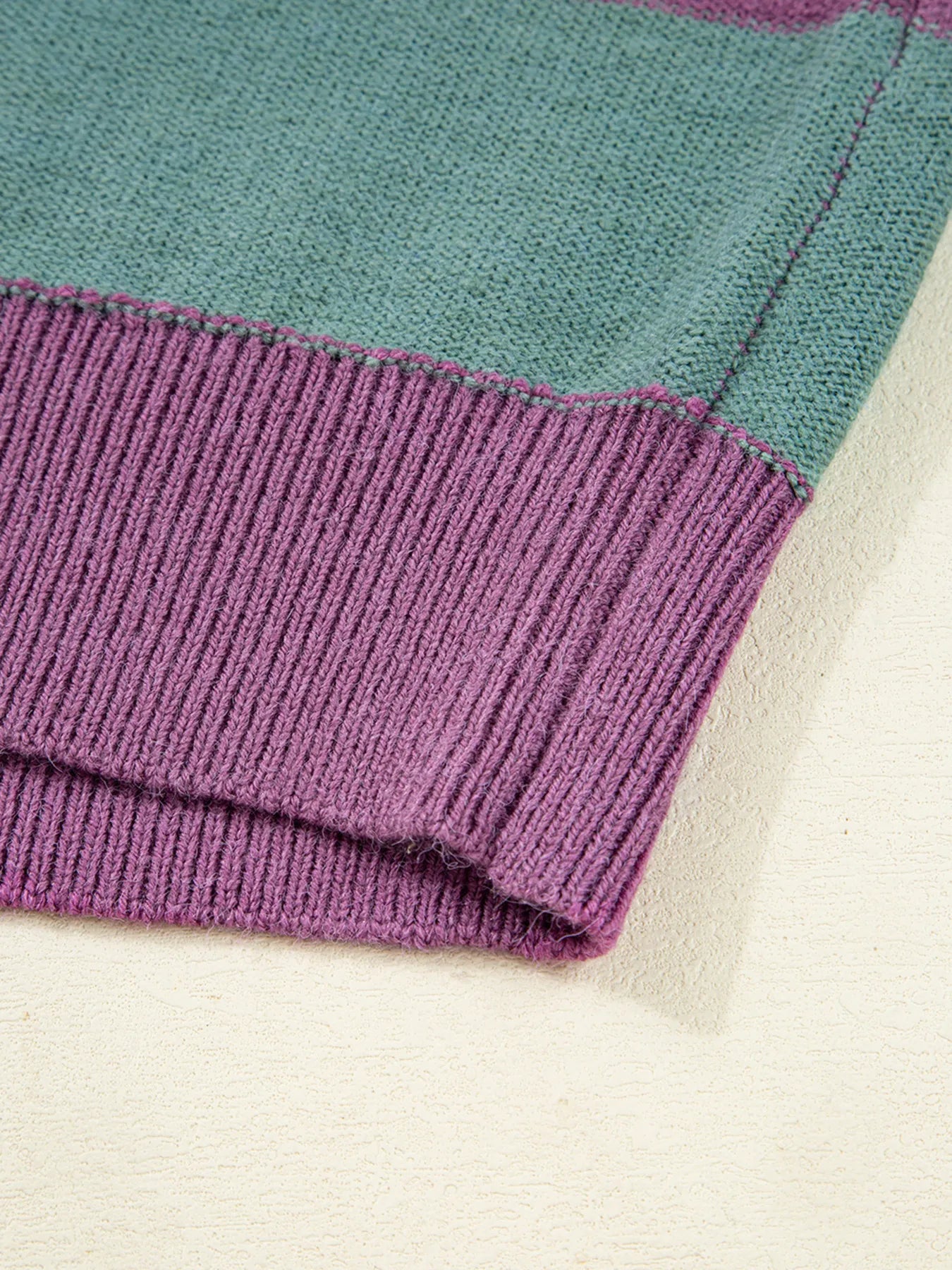 Close-up of a folded fabric with purple and teal edges on a white background